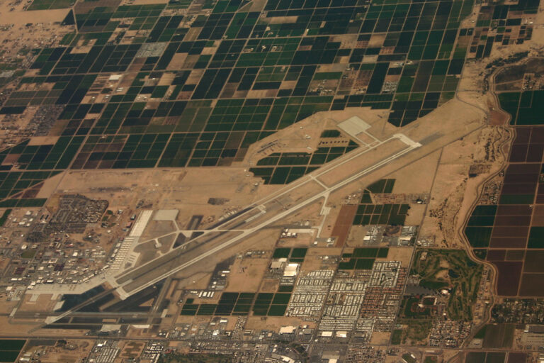 Photo: formulanone - aerial view of an airport surrounded by farmland, roads, and buildings, with runways and taxiways visible.