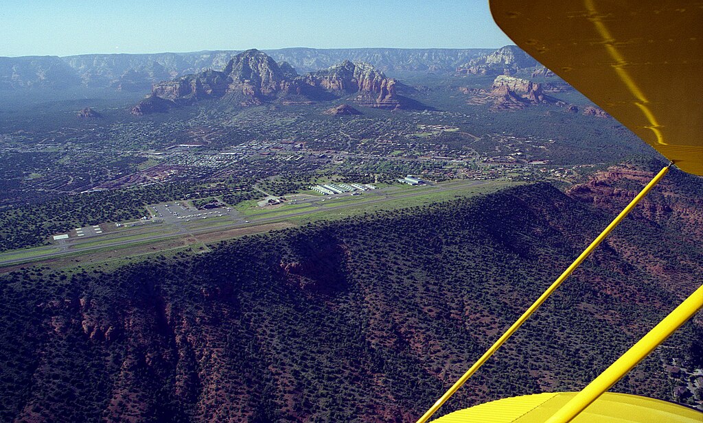 aerial view of sedona airport on a plateau, with mountains and town below, seen from a yellow aeroplane in sedona, arizona.