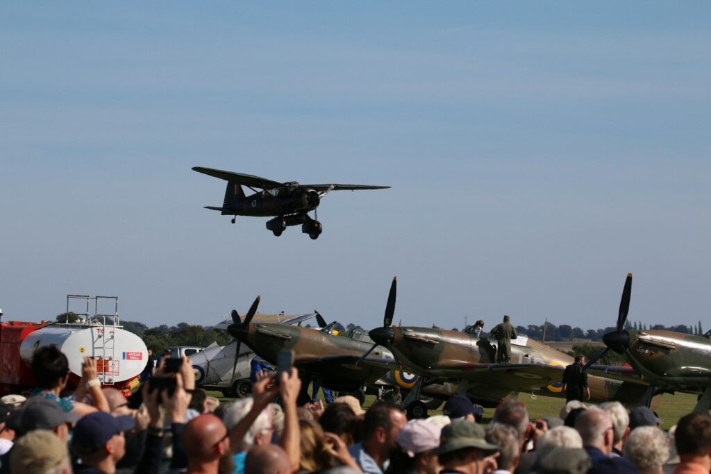 A biplane flies overhead at an airshow.