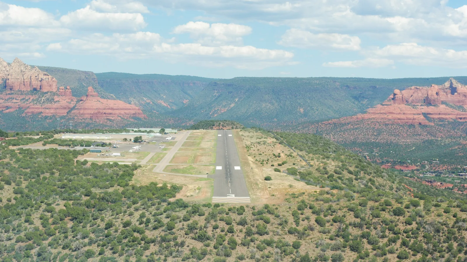 Aerial view on approach to the mesa-top runway at Sedona Airport, Arizona, with red rock cliffs behind