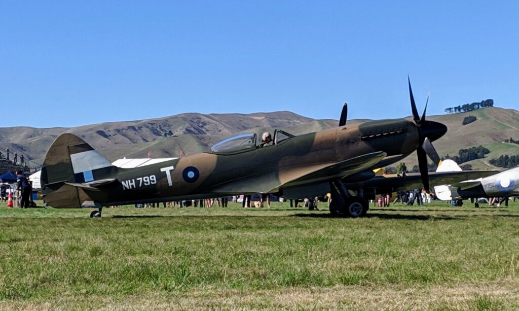 Spitfire NH799 parked on the grass at Omaka Aerodrome with the Marlborough hills behind