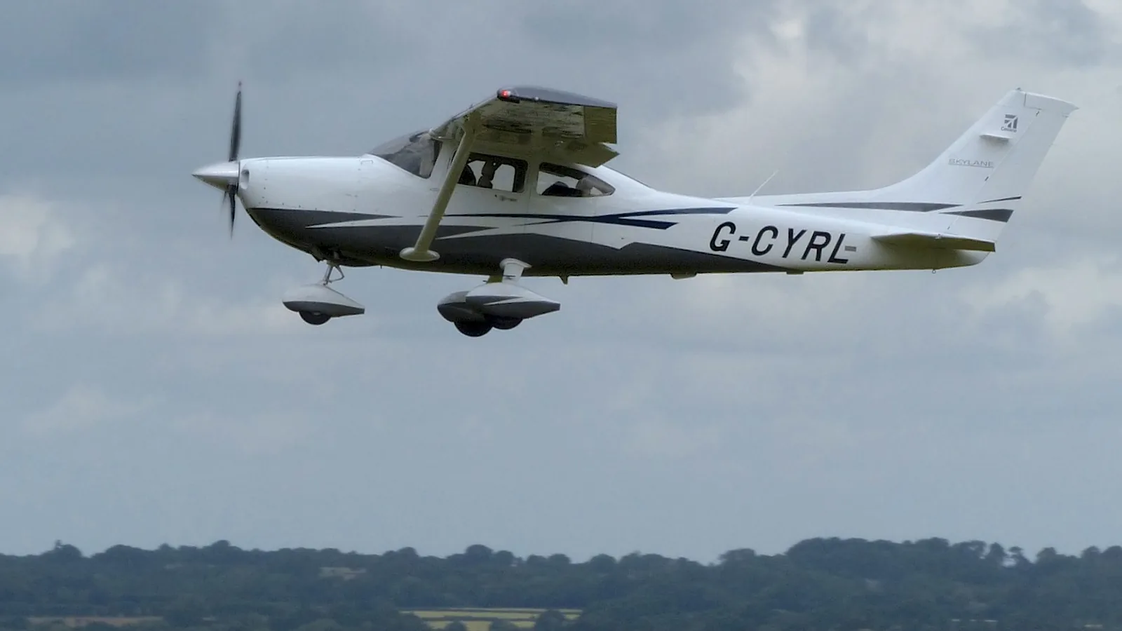 Cessna 182 light aircraft G-CYRL in flight at Compton Abbas airfield, Dorset