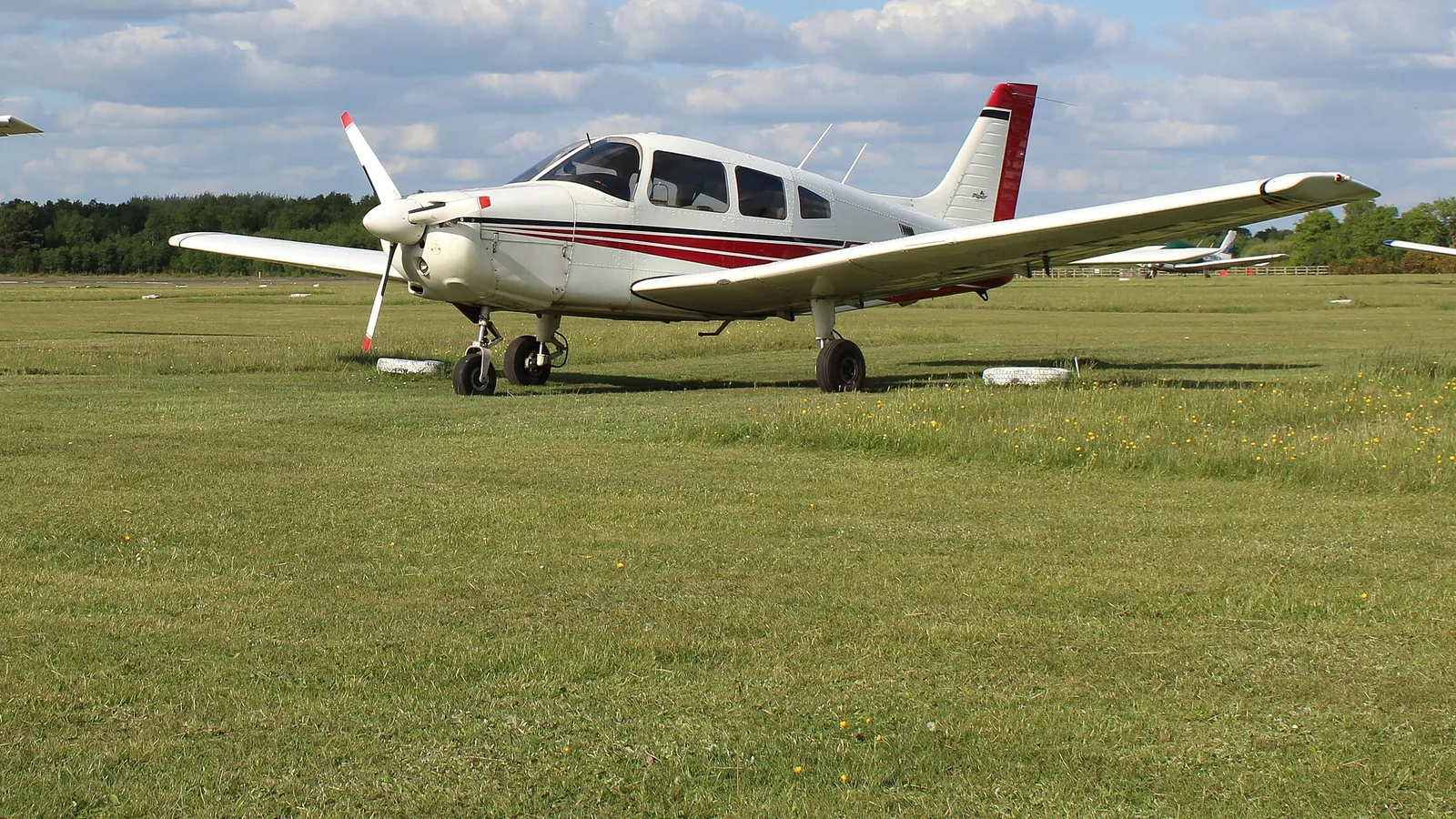 Piper light aircraft parked on the grass at Blackbushe Airport, Hampshire